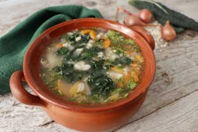 Clear soup with chicken. kale, carrots, shallot onion and parsley in brown bowls