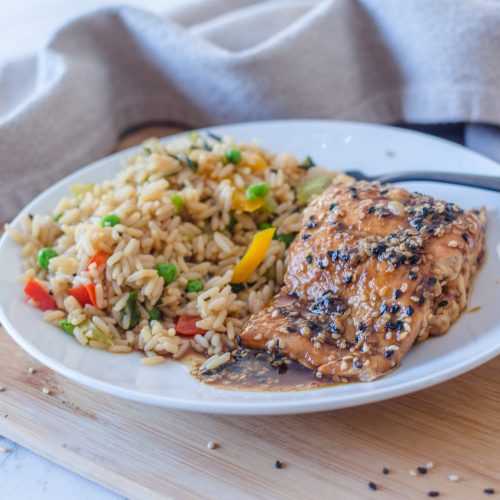 Salmon fillet topped with spices alongside rice and chopped vegetables