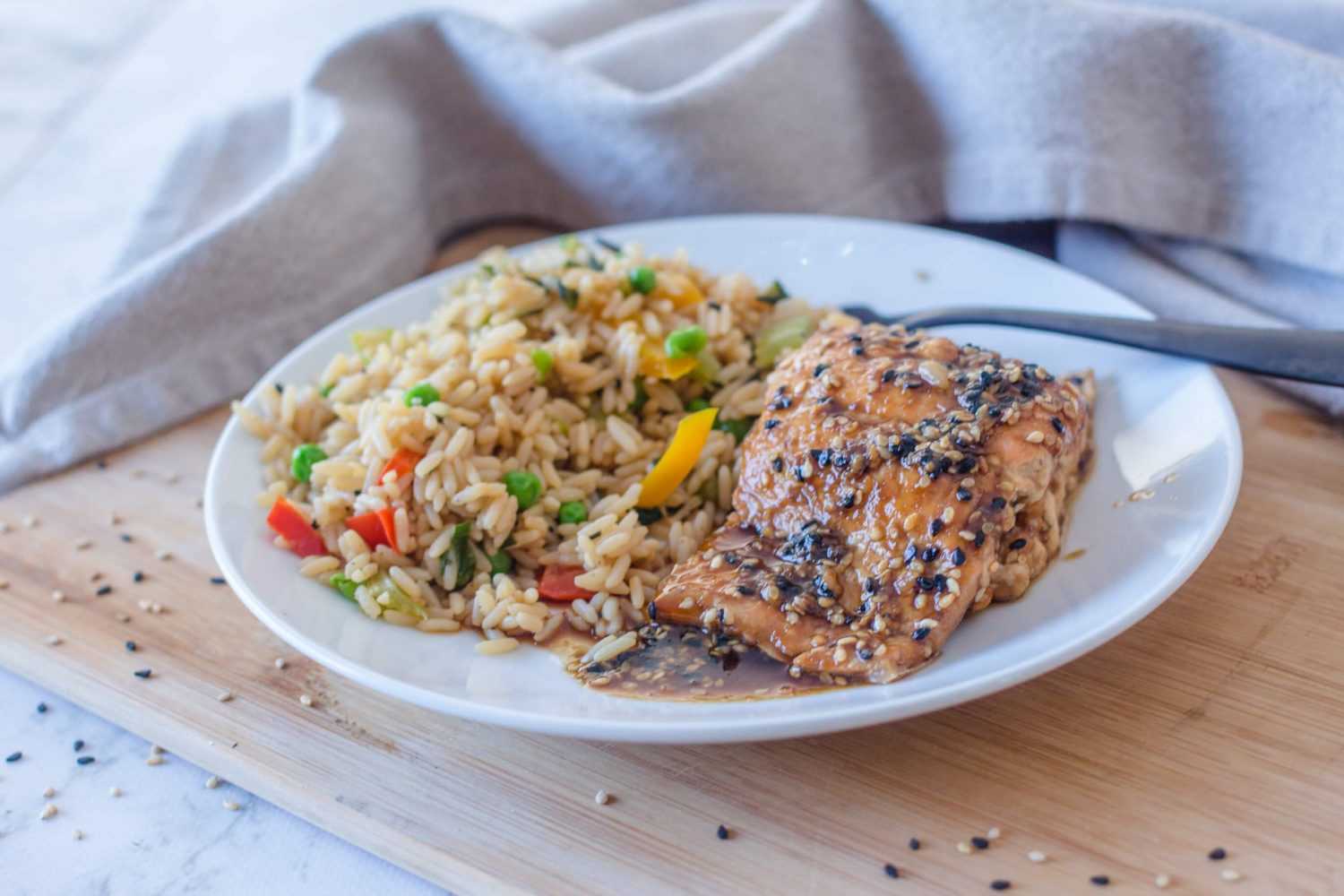 Salmon fillet topped with spices alongside rice and chopped vegetables