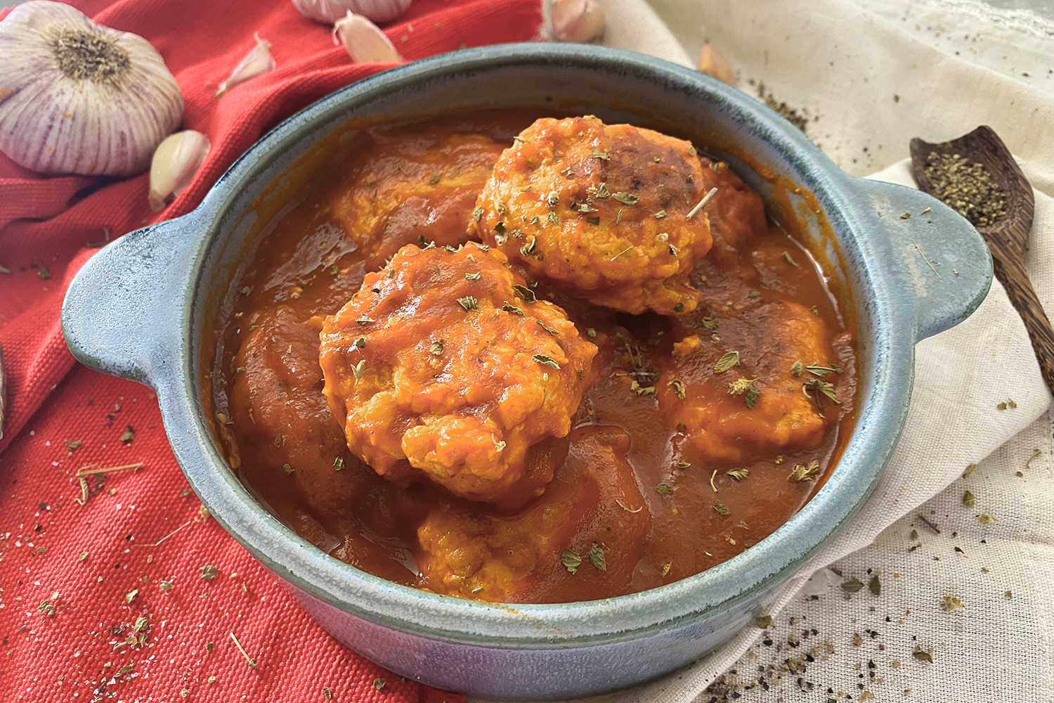 Chicken Meatballs in tomato sauce in a blue bowl with oregano on top