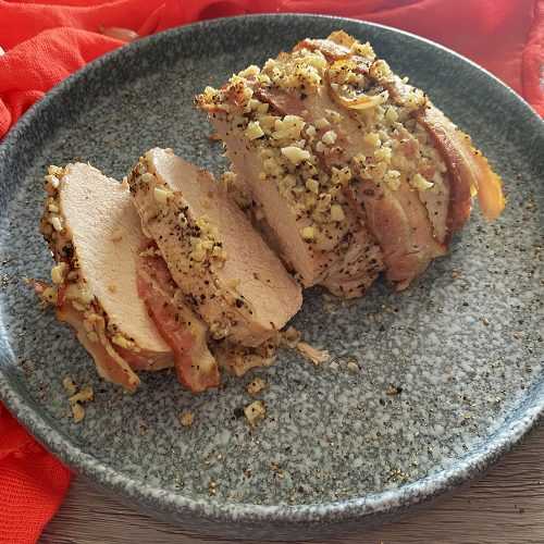 Pork loin slices topped with minced garlic and ground black pepper on a gray plate