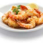 Fried shrimp in garlic sauce with parsley and slice of lemon in white plate