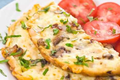 Omelette with mushrooms, cheese and chopped coriander with tomato slices on side