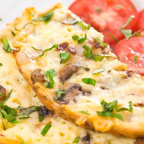 Omelette with mushrooms, cheese and chopped coriander with tomato slices on side
