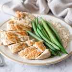 Chicken breasts slices topped with spices alongside whole green bean and jasmine rice