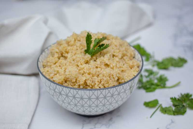 Cooked quinoa in a gray bowl with parsley on top