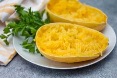Spaghetti squash cut in half with parsley on white plate