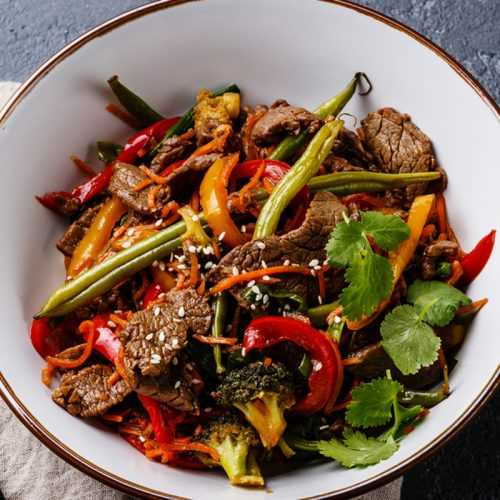 beef strips with green bean, broccoli florets and red and orange bell peppers topped with cilantro