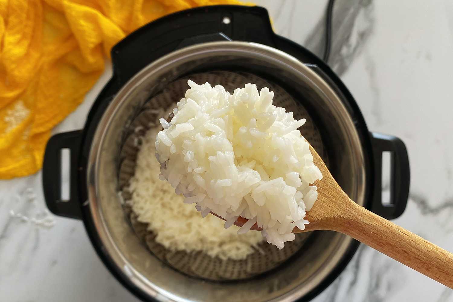 Instant Pot and a wooden spoon with cooked rice