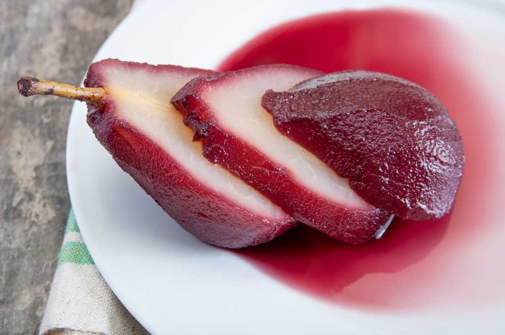 Poached pears sliced in red whine in white plate