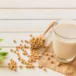 Soy milk in a glass with dried soybeans on side