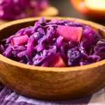 Sliced red cabbage with apple cubes in a wooden bowl