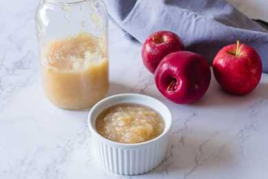 Apple sauce in a small bowl and in a jar with red apples on side
