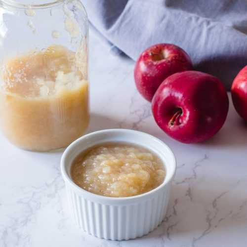 Apple sauce in a small bowl and in a jar with red apples on side