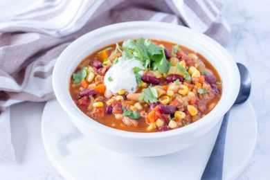 Chili soup filled with ground beef, red bean, corn and carrot and topped with yogurt and parsley
