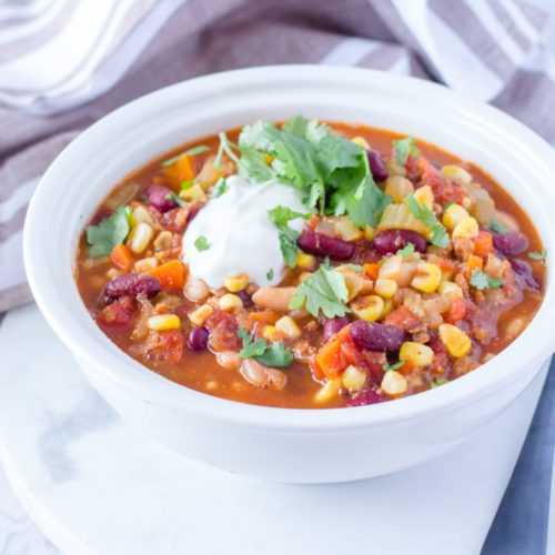 Chili soup filled with ground beef, red bean, corn and carrot and topped with yogurt and parsley