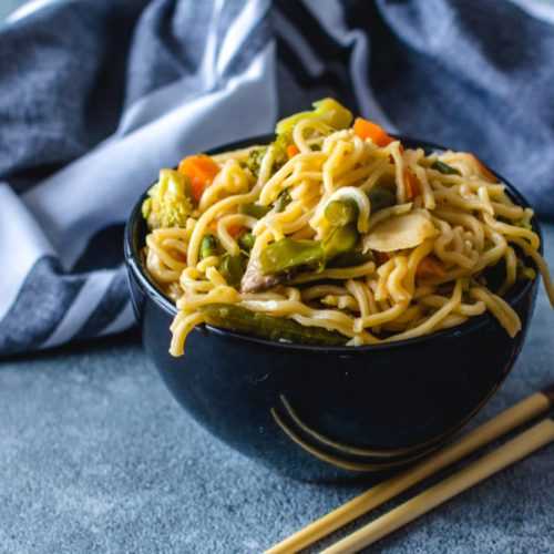 Ramen noodles with broccoli, bell pepper, carrot, onion and spices with chopsticks on side