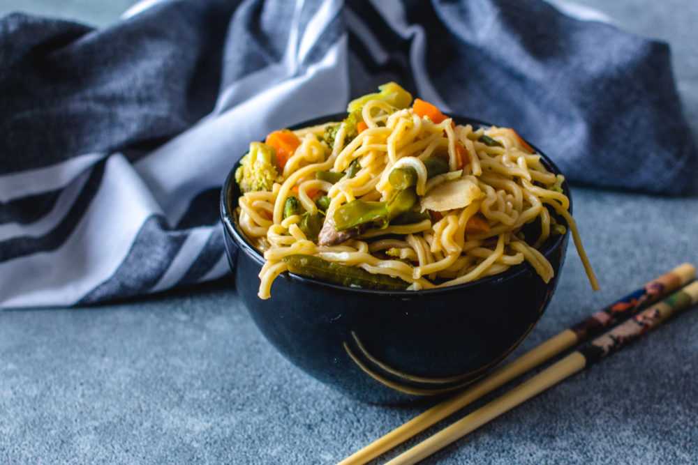 Ramen noodles with broccoli, bell pepper, carrot, onion and spices with chopsticks on side