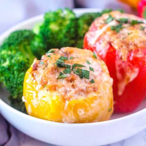 Red and yellow bell peppers topped with melted cheese and parsley with broccoli florets on side