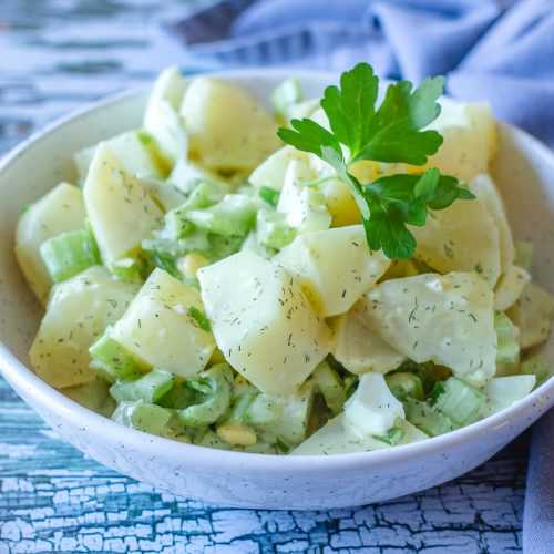 potato salad with onion and eggs and parsley leaves on top