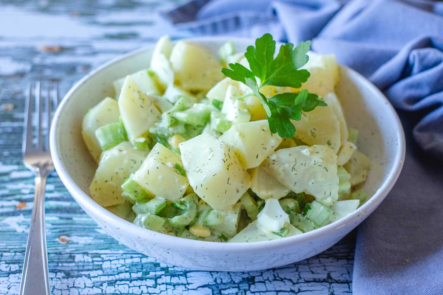 potato salad with chopped celery, eggs and parsley leaves on top
