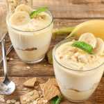 Banana pudding in two glasses with banana slices and mint on top with whole bananas on side