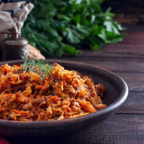 Sliced cabbage mixed with sausage and pork cubes in red sauce