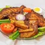 Fried pomfret with egg, tomato, red onion and lettuce on a plate