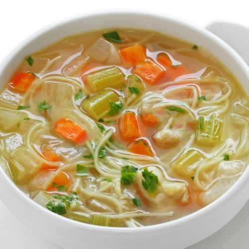 Clear soup with egg noodles, shredded chicken, celery and carrot