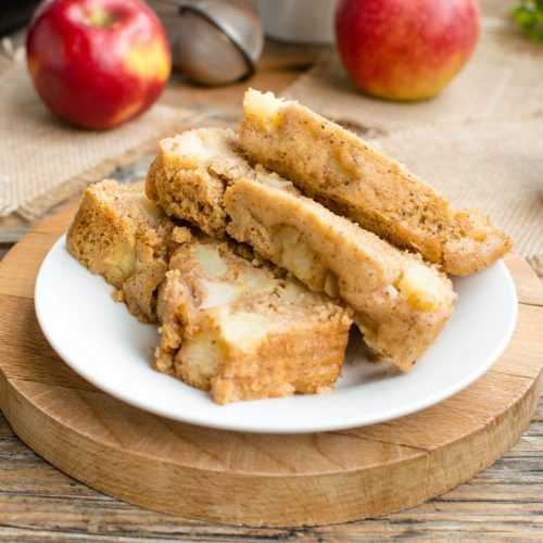 Three slices of apple bread on a plate with red apples on side