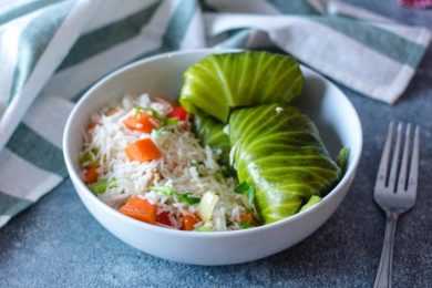 Stuffed cabbage rolls alongside white rice with vegetables