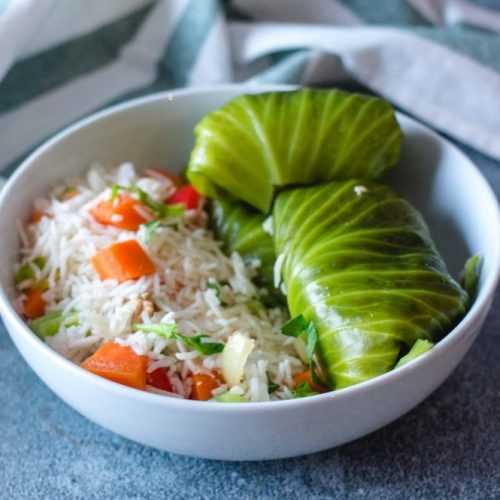 Stuffed cabbage rolls alongside white rice with vegetables