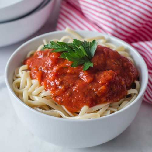 Cooked spaghetti topped with red marinara sauce and parsley