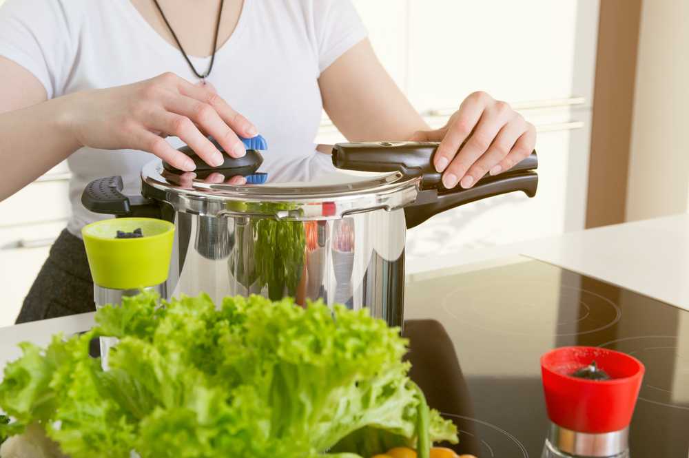 girl holding a pressure cooker on a stovetop
