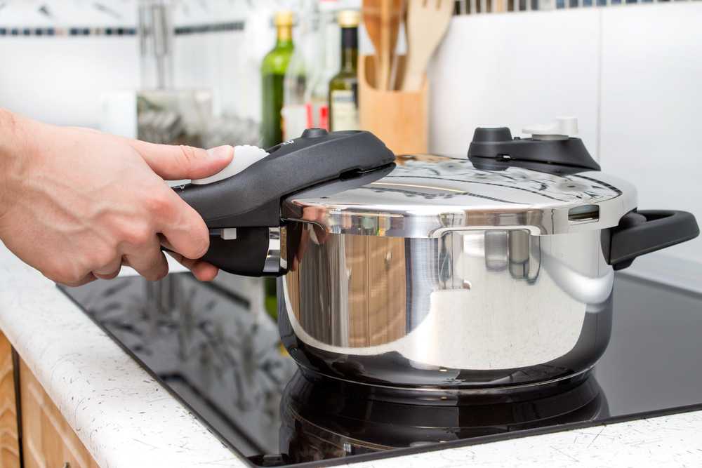 hand holding small pressure cooker on stovetop
