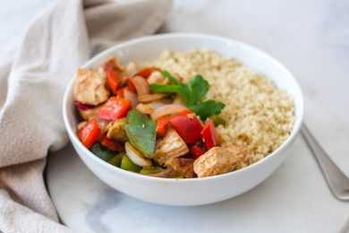 chicken cubes with green and red bell pepper cubes with white rice and parsley leaf on top