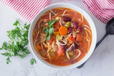 Minestrone soup with pasta noodles, carrot, celery, red beans and parsley