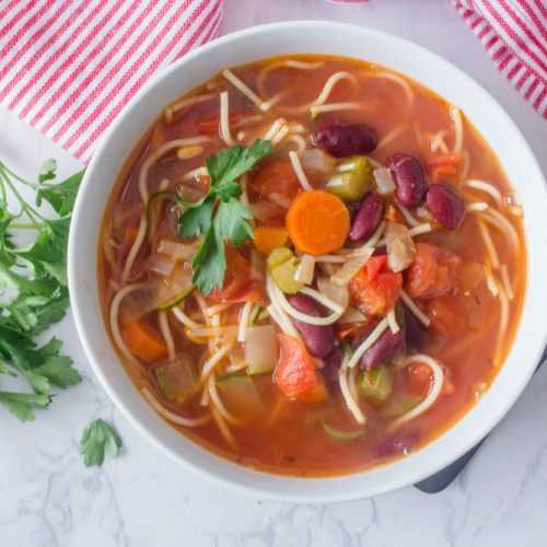 Minestrone soup with pasta noodles, carrot, celery, red beans and parsley