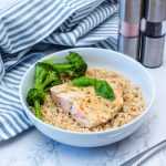 Salmon fillet over brown rice with broccoli florets on side in white bowl