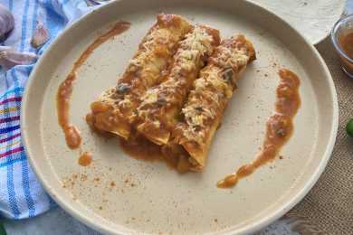 Three chicken enchiladas topped with red sauce and melted cheese on white plate