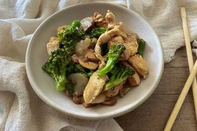 Chicken pieces mixed with cooked broccoli florets and roasted mushrooms in a white bowl