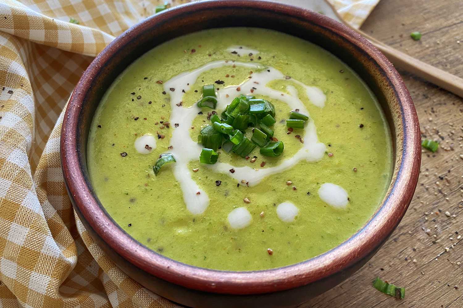 Zucchini Soup in a brown bowl topped with chopped scallion and coconut milk