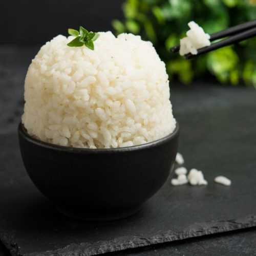 Basmati rice in a black bowl topped with basil