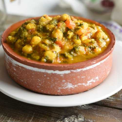 Chickpea curry with kale, okra, corn, bell peppers and spices in brown bowl
