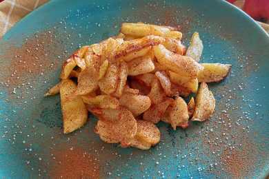 Fried Apple slices topped with cinnamon and sugar on a blue plate
