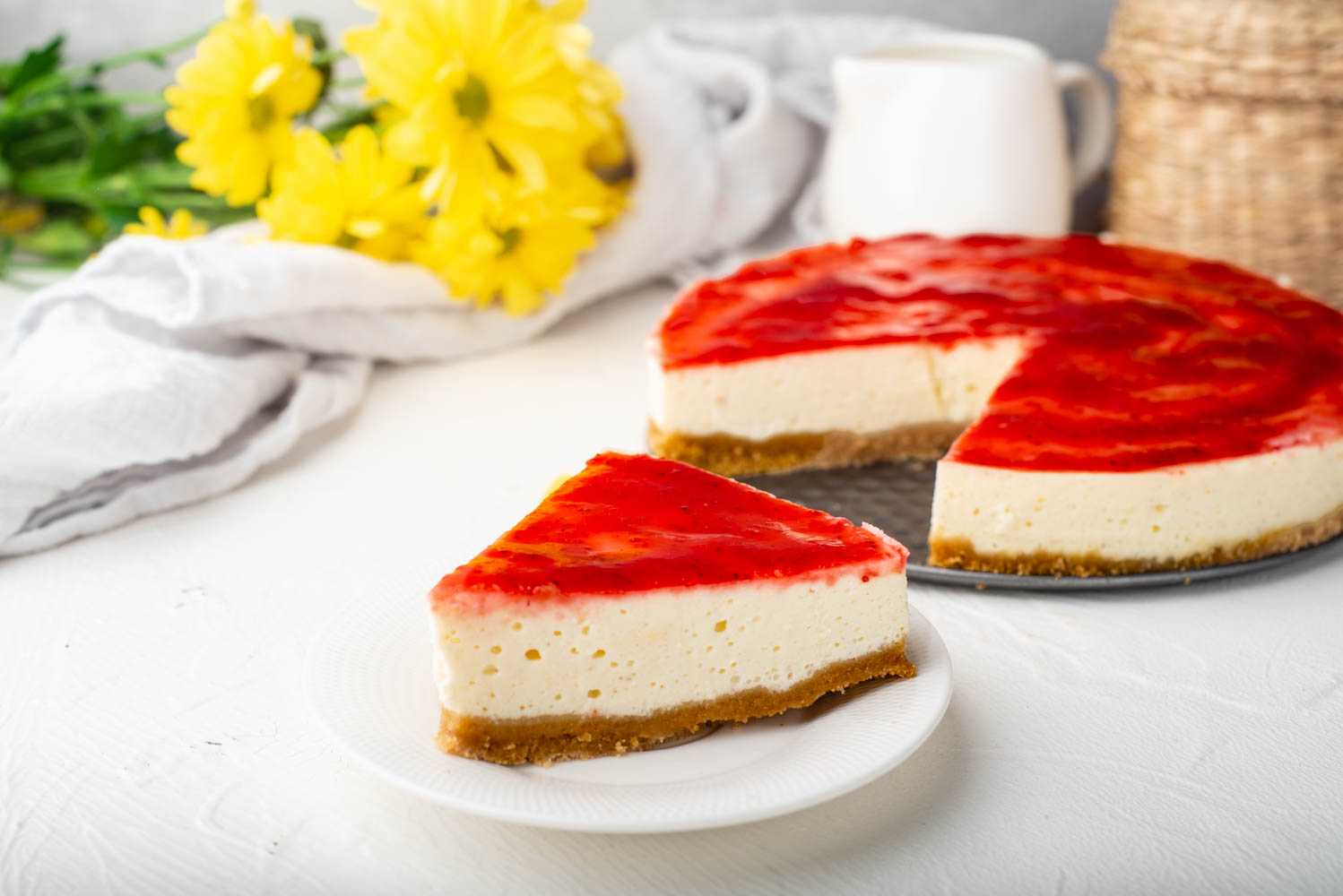 Cheesecake slice with strawberry jam on top and crust on the bottom