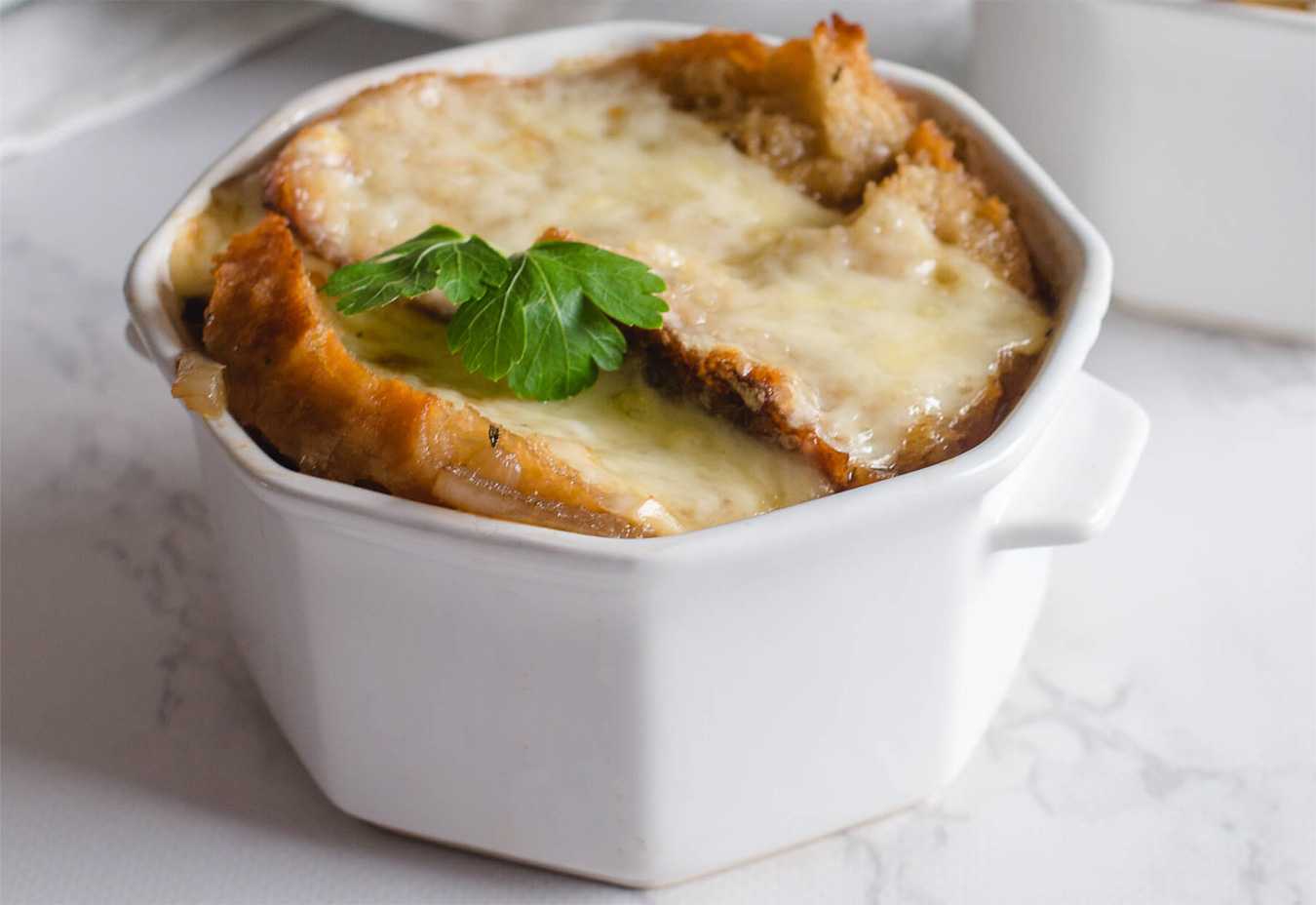Onion soup topped with baguette slices, melted cheese and parsley