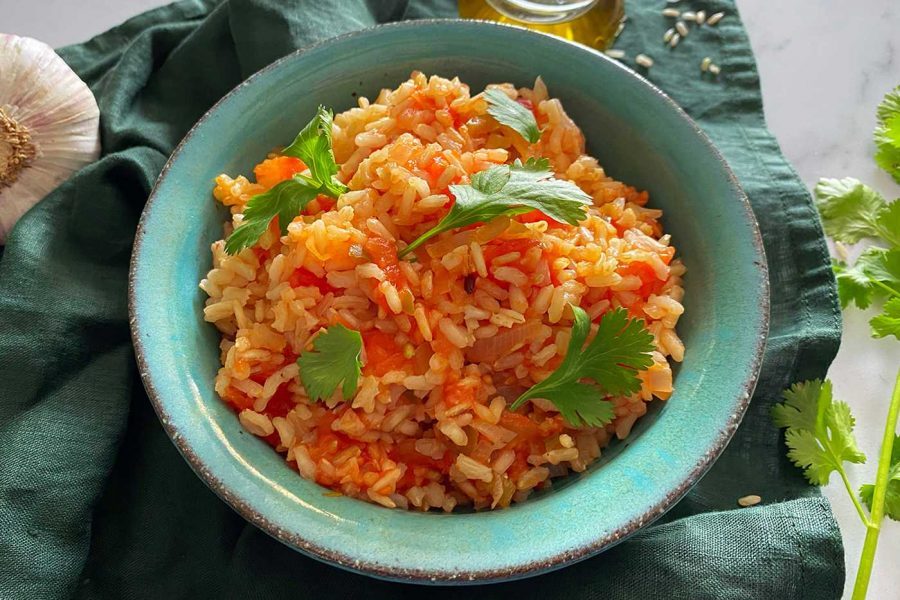 yellow rice in tomato sauce topped with parsley leaves in a blue plate