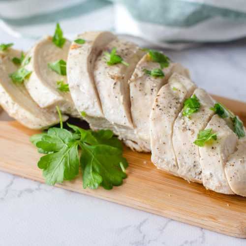 Turkey breast cut into slices with parsley on cutter board