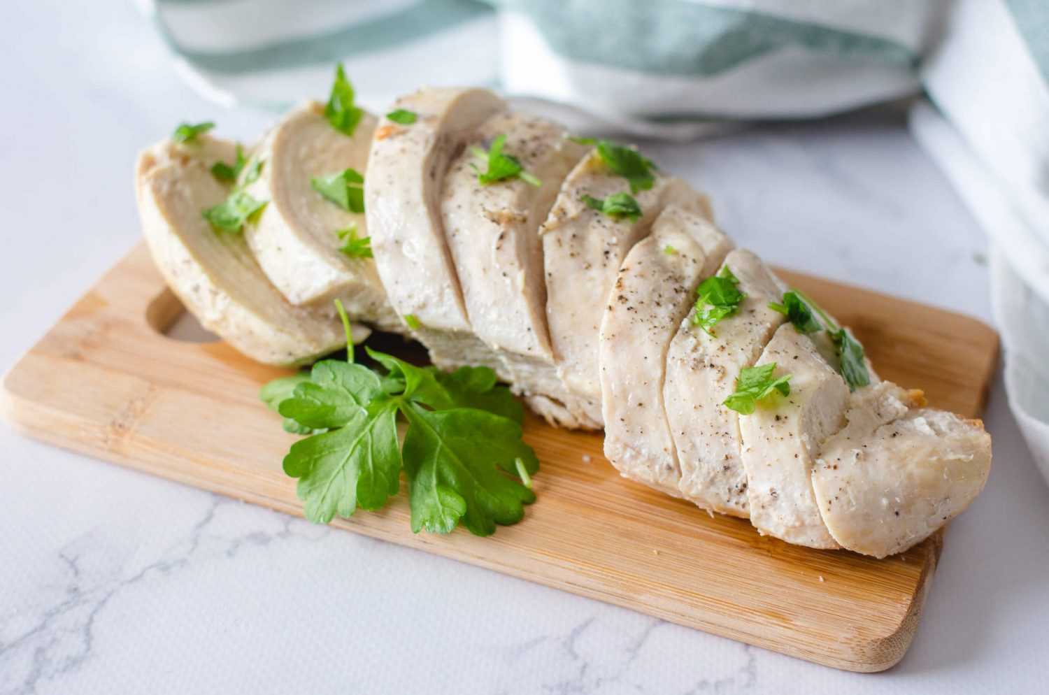 Turkey breast cut into slices with parsley and black pepper on cutter board